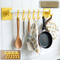 Wall mounted kitchen rack with adhesive hooks holding kitchen accessories