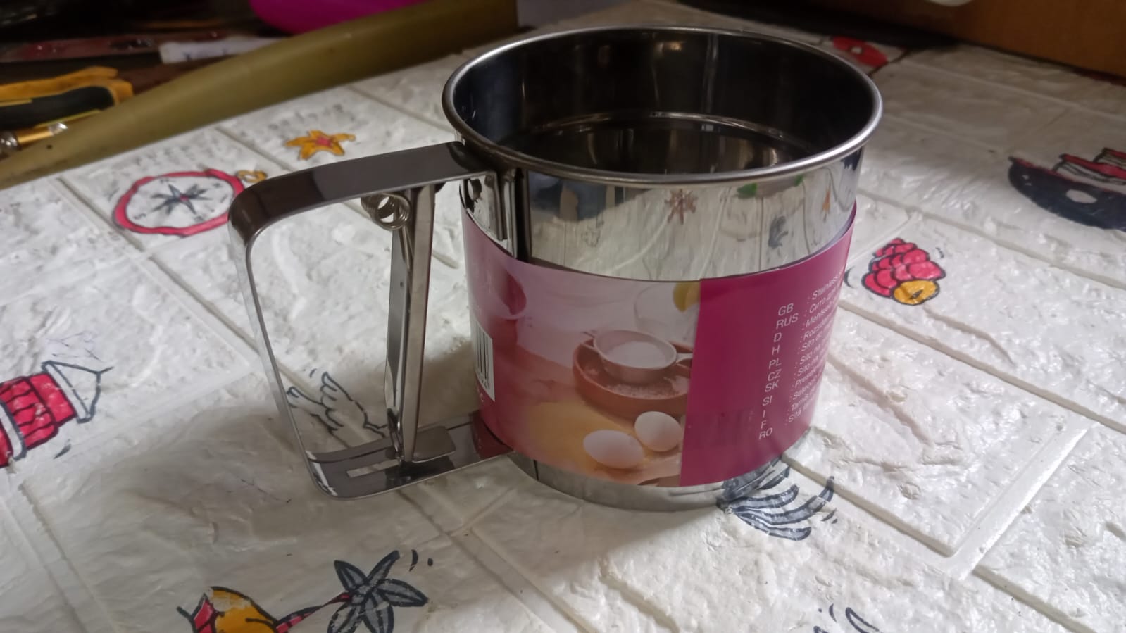 Detailed view of the handheld flour sifter, showcasing its fine mesh screen.