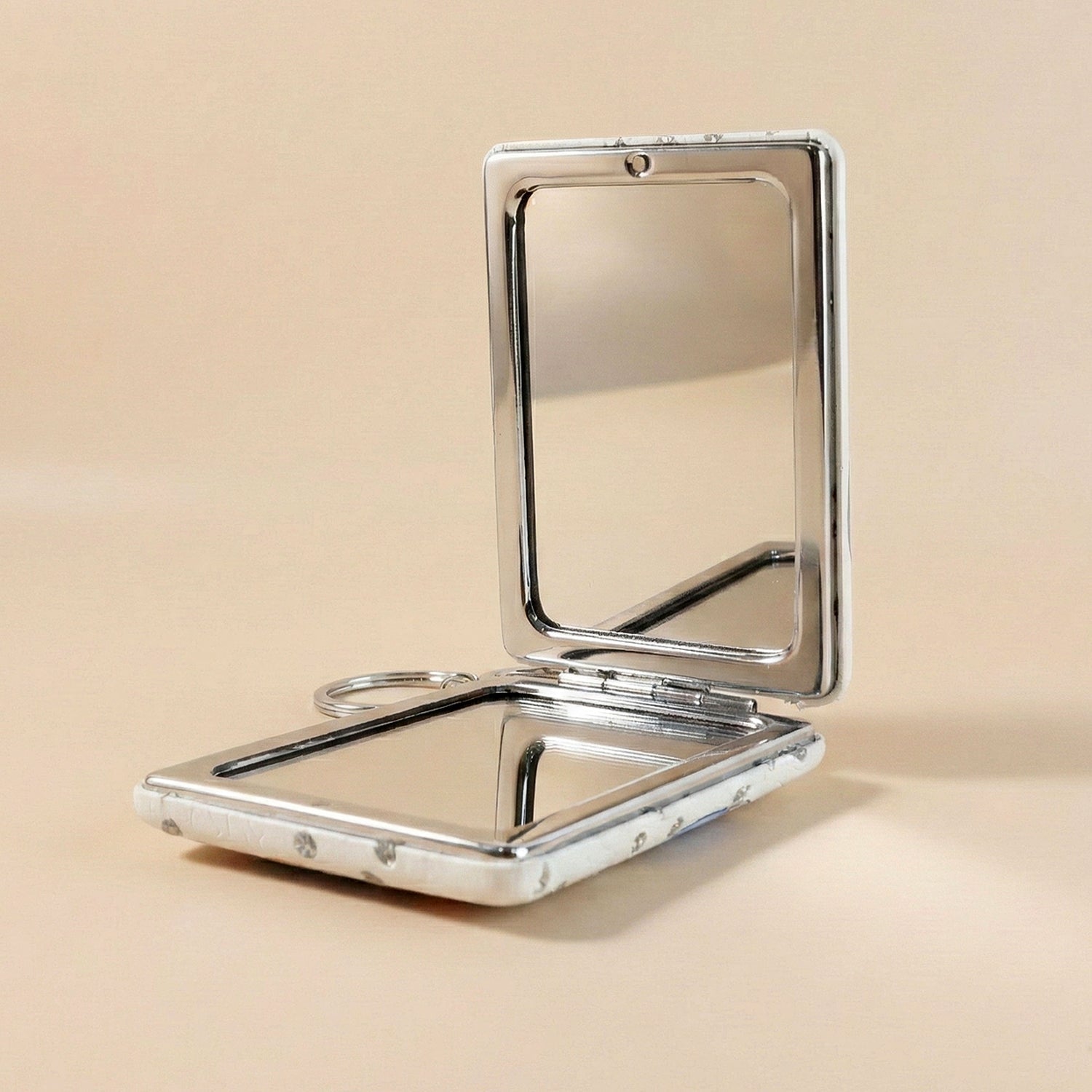 Foldable compact mirror keychain demonstrating dual-sided mirrors