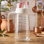 Close-up of glass oil dispenser bottle showing pouring action and side handle