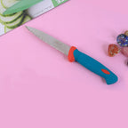 Hand holding the stainless steel paring knife over a cutting board