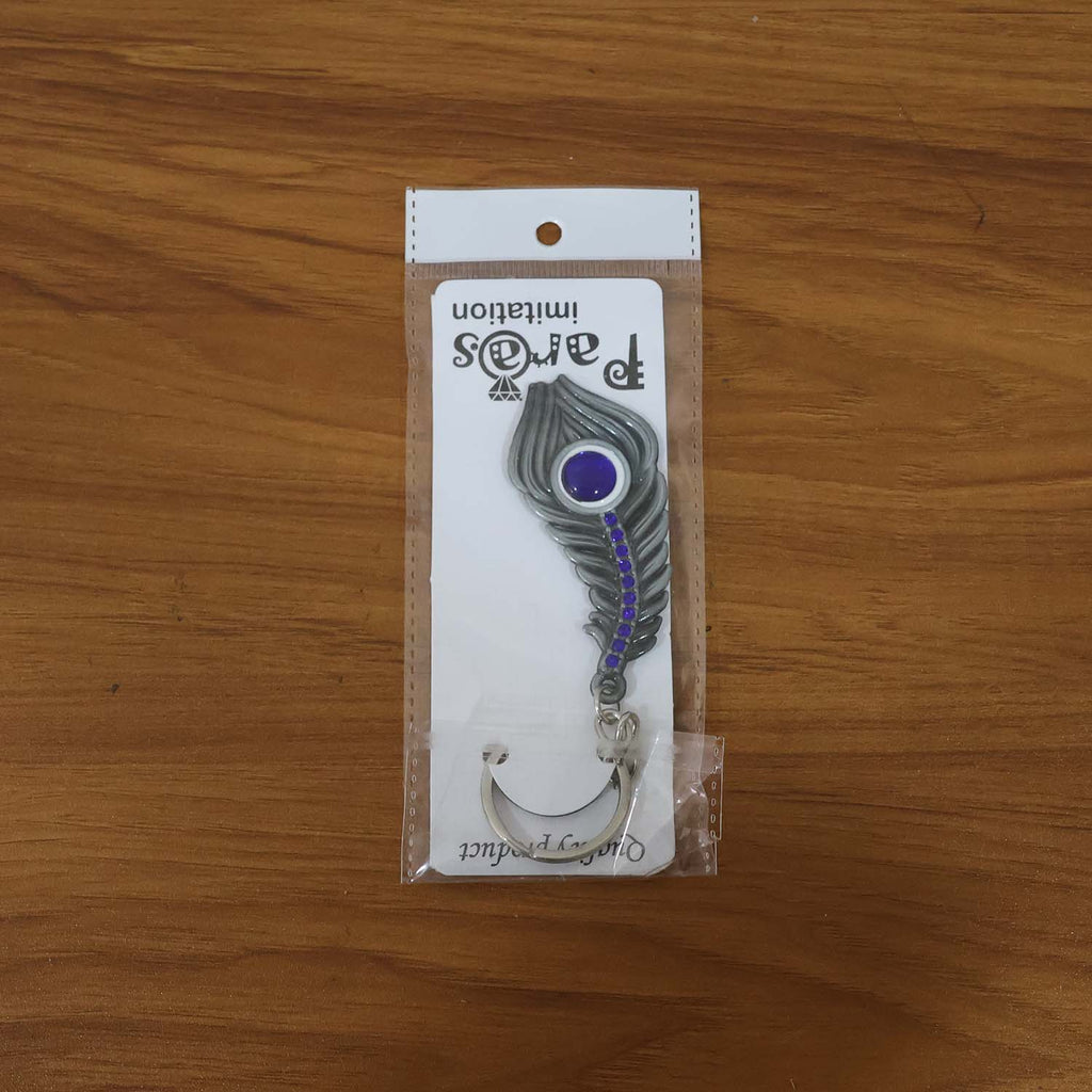 Peacock feather metal keychain shown in lifestyle setting with keys