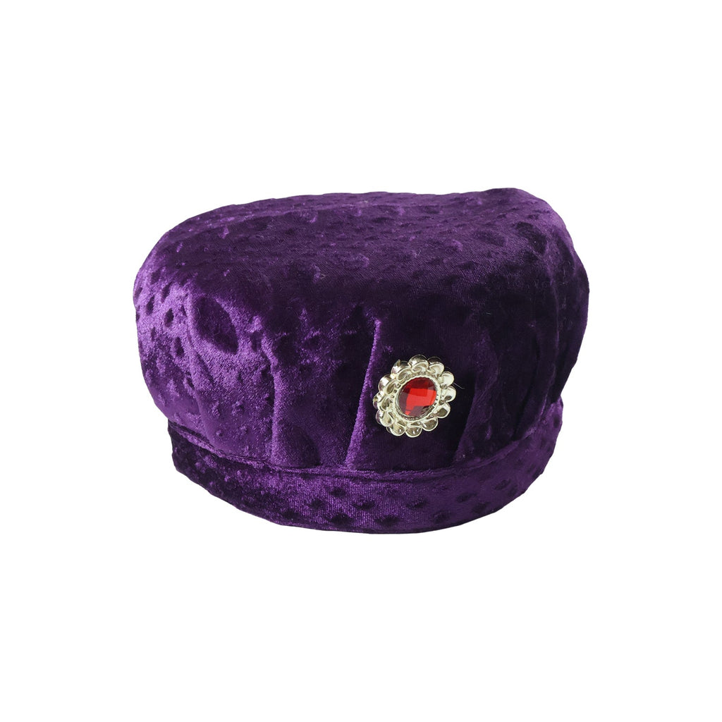 Boy wearing velvet traditional cap with stone brooch in festive setting