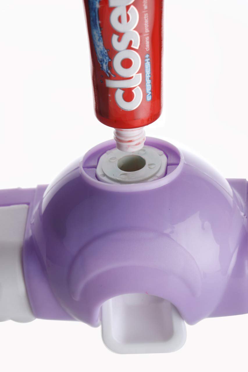 White automatic toothpaste dispenser and 4-slot toothbrush holder mounted on a wall.