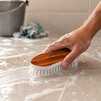 Cloth washing brush being used to clean tiles with nylon bristles