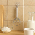 Two stainless steel spiral hand whisks hanging on adhesive wall hooks