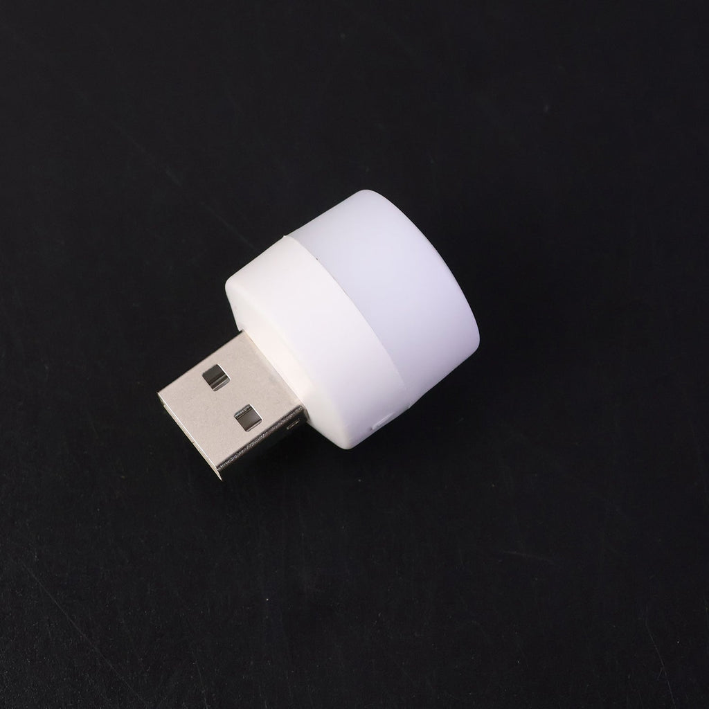 Mini portable yellow USB LED night light glowing beside a laptop keyboard
